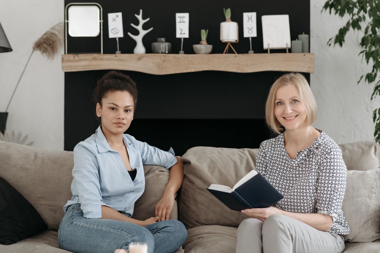 Two women sitting on a sofa engaged in conversation in a stylish living room.