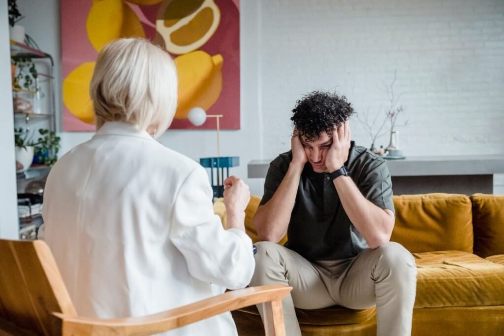 A therapist consults a distressed man in a cozy setting.